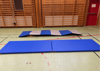 Hinderbana i gympasal – En station med sluttande mattor som tränar balans, smidighet och koordination. Barnen kan gå, springa eller krypa över de ojämna mattorna.