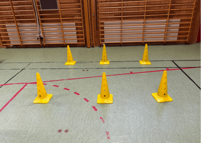 Hinderbana i gympasal – En station med koner som tränar smidighet och koordination. Barnen kan springa slalom mellan konerna eller hoppa över dem för att utmana sin balans och snabbhet.